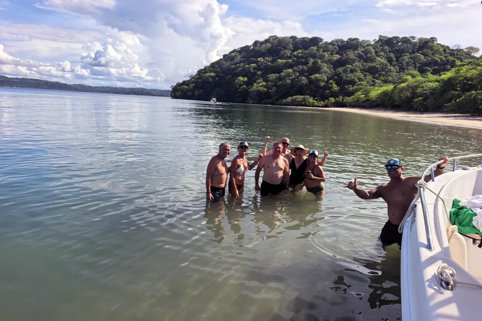 Tour guests standing in shallow water beside the boat at a beach in the Gulf of Papagayo